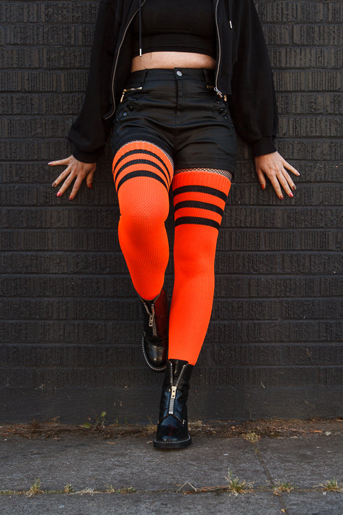 A person wearing Electric Shock thigh highs in neon orange with black stripes