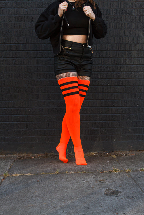 A person wearing Electric Shock thigh highs in neon orange with black stripes