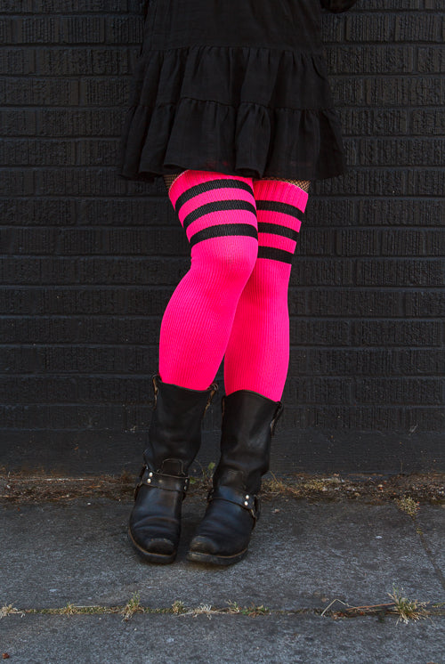 A person wearing Electric Shock thigh highs in neon pink with black stripes