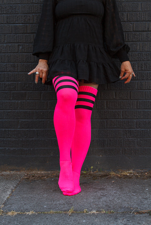 A person wearing Electric Shock thigh highs in neon pink with black stripes