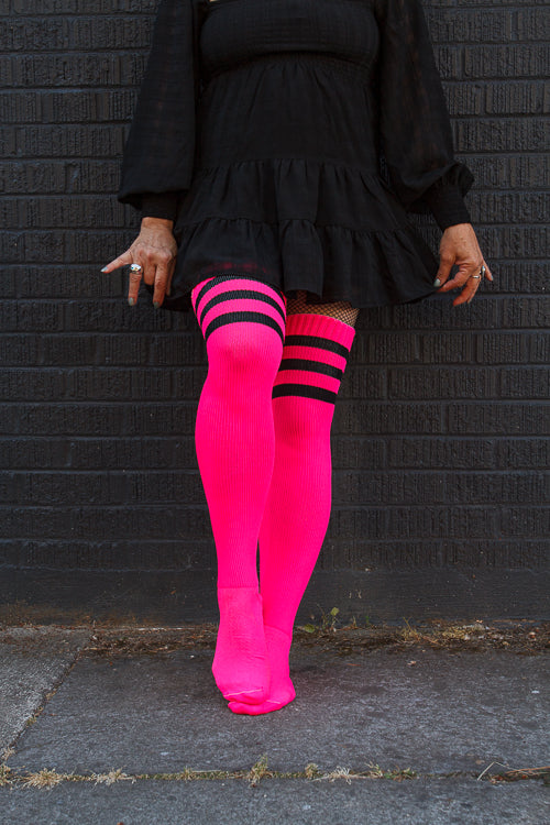 A person wearing Electric Shock thigh highs in neon pink with black stripes