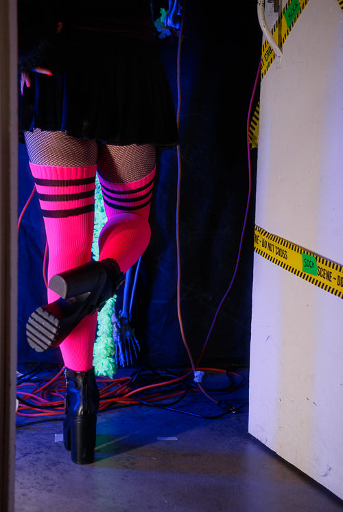 A person wearing Electric Shock thigh highs in neon pink with black stripes