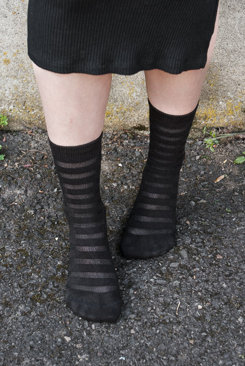 A person wearing Gossamer striped crew socks in black