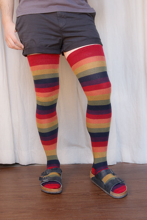 A person wearing XL foot longer harvest rainbow thigh highs in rainbow stripes