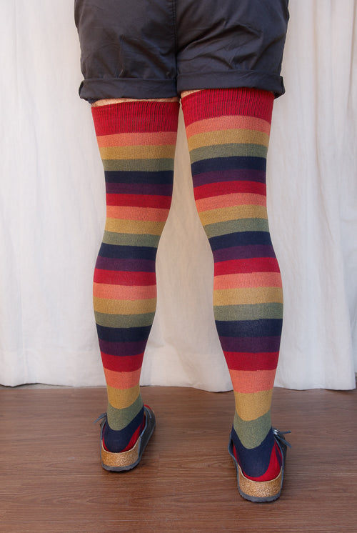 A person wearing XL foot longer harvest rainbow thigh highs in rainbow stripes