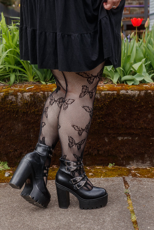 A person wearing Plus size butterfly net tights in black
