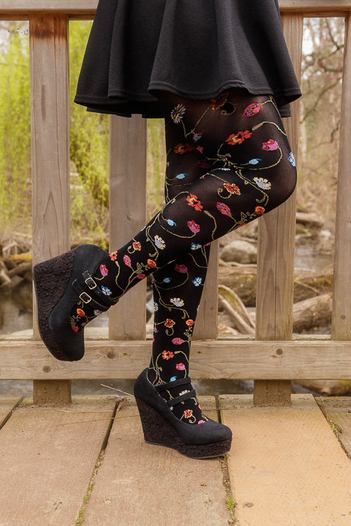 A person wearing Platino floral tights with colorful flowers