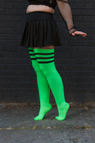 A person wearing Electric Shock thigh highs in neon green with black stripes