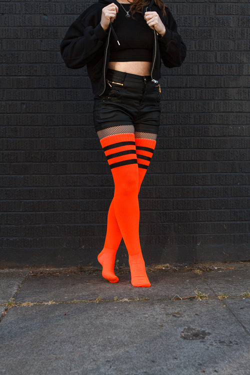 A person wearing Electric Shock thigh highs in neon orange with black stripes