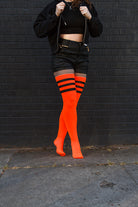 A person wearing Electric Shock thigh highs in neon orange with black stripes