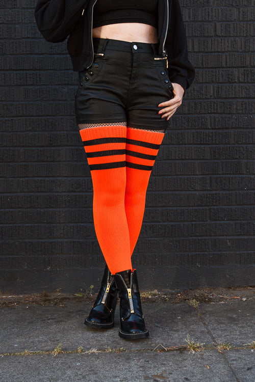 A person wearing Electric Shock thigh highs in neon orange with black stripes