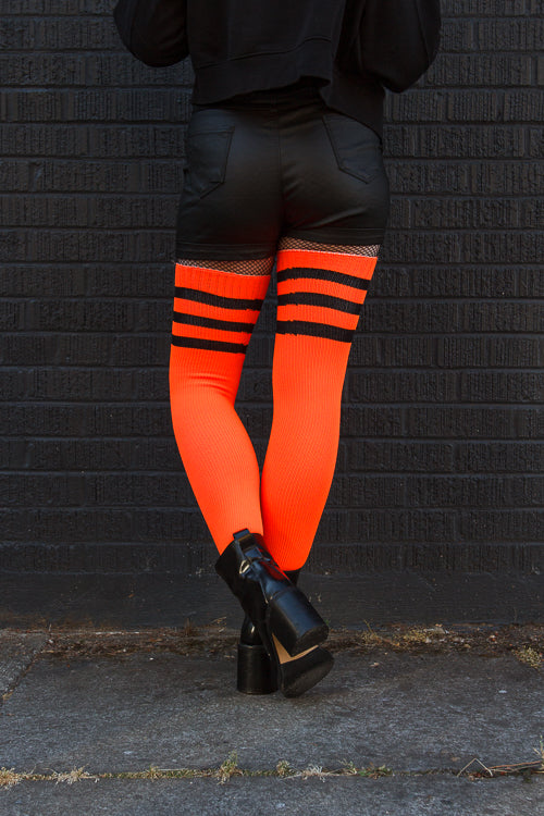 A person wearing Electric Shock thigh highs in neon orange with black stripes