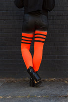 A person wearing Electric Shock thigh highs in neon orange with black stripes