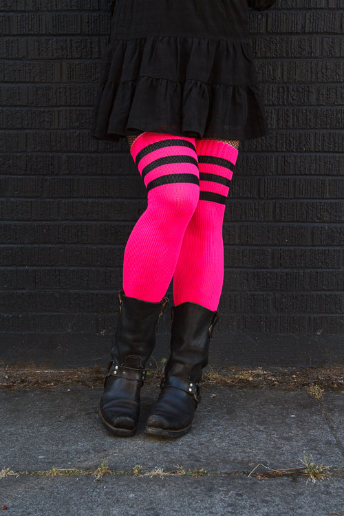 A person wearing Electric Shock thigh highs in neon pink with black stripes