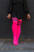 A person wearing Electric Shock thigh highs in neon pink with black stripes