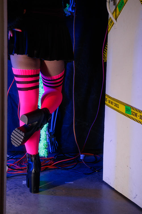 A person wearing Electric Shock thigh highs in neon pink with black stripes