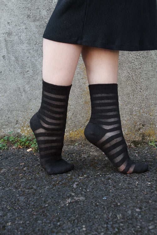 A person wearing Gossamer striped crew socks in black