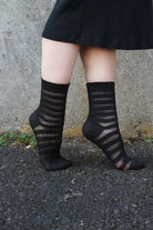 A person wearing Gossamer striped crew socks in black