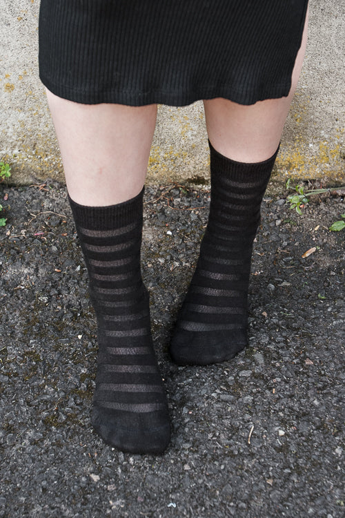 A person wearing Gossamer striped crew socks in black