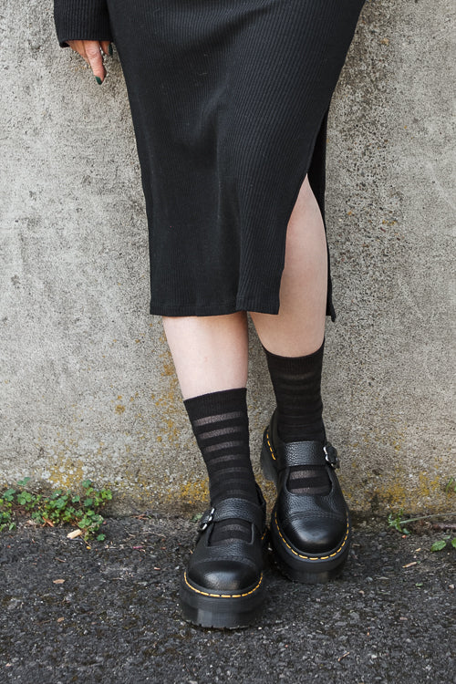 A person wearing Gossamer striped crew socks in black