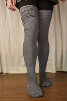 A person wearing larger-footed long cuffable scrunchable socks in charcoal