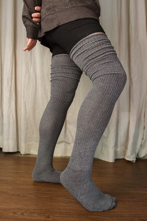 A person wearing larger-footed long cuffable scrunchable socks in charcoal