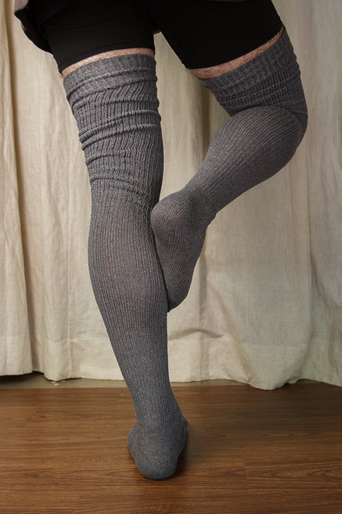 A person wearing larger-footed long cuffable scrunchable socks in charcoal