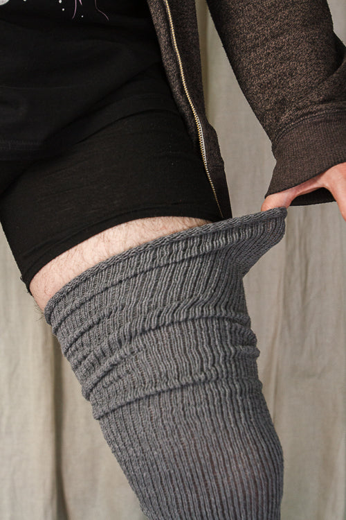 A person wearing larger-footed long cuffable scrunchable socks in charcoal