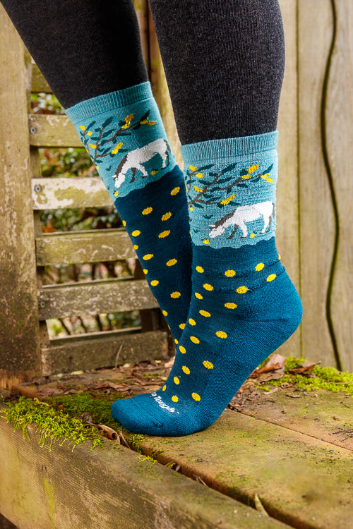 A person wearing unicorn wildlife crew socks in dark teal