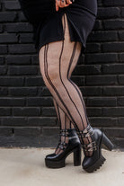 a person wearing plus size pin dot vertical striped fishnet tights in black
