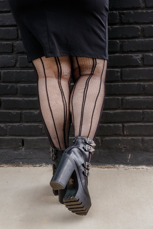 a person wearing plus size pin dot vertical striped fishnet tights in black