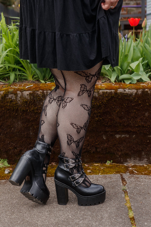A person wearing Plus size butterfly net tights in black