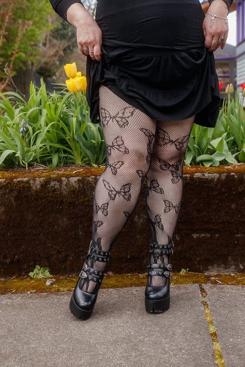 A person wearing Plus size butterfly net tights in black