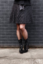 A person wearing lace ruffle anklets with mini bows in black on black