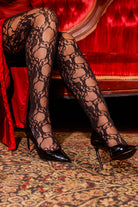 A person wearing floral lace thigh highs with stay-up lace top