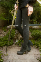 Person wearing dark charcoal thigh highs with a sword design down the front