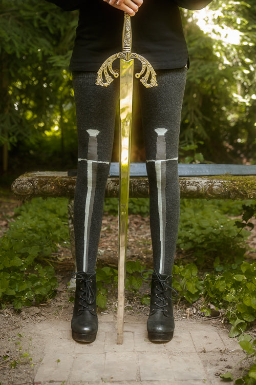 Person wearing dark charcoal thigh highs with a sword design down the front
