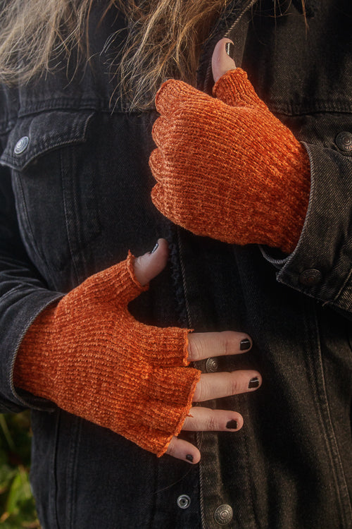 A person wearing chenille fingerless gloves in pumpkin