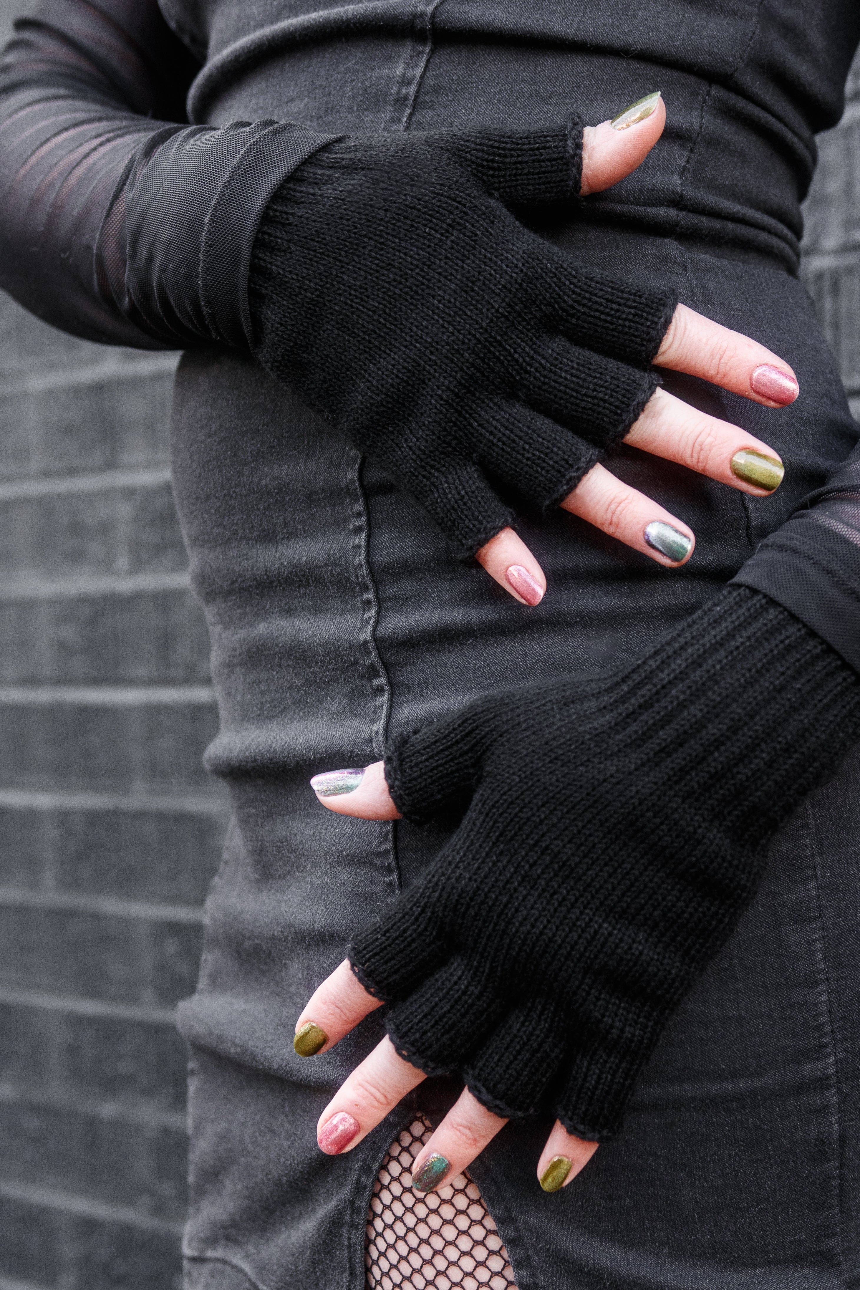 A person wearing knit fingerless gloves in black