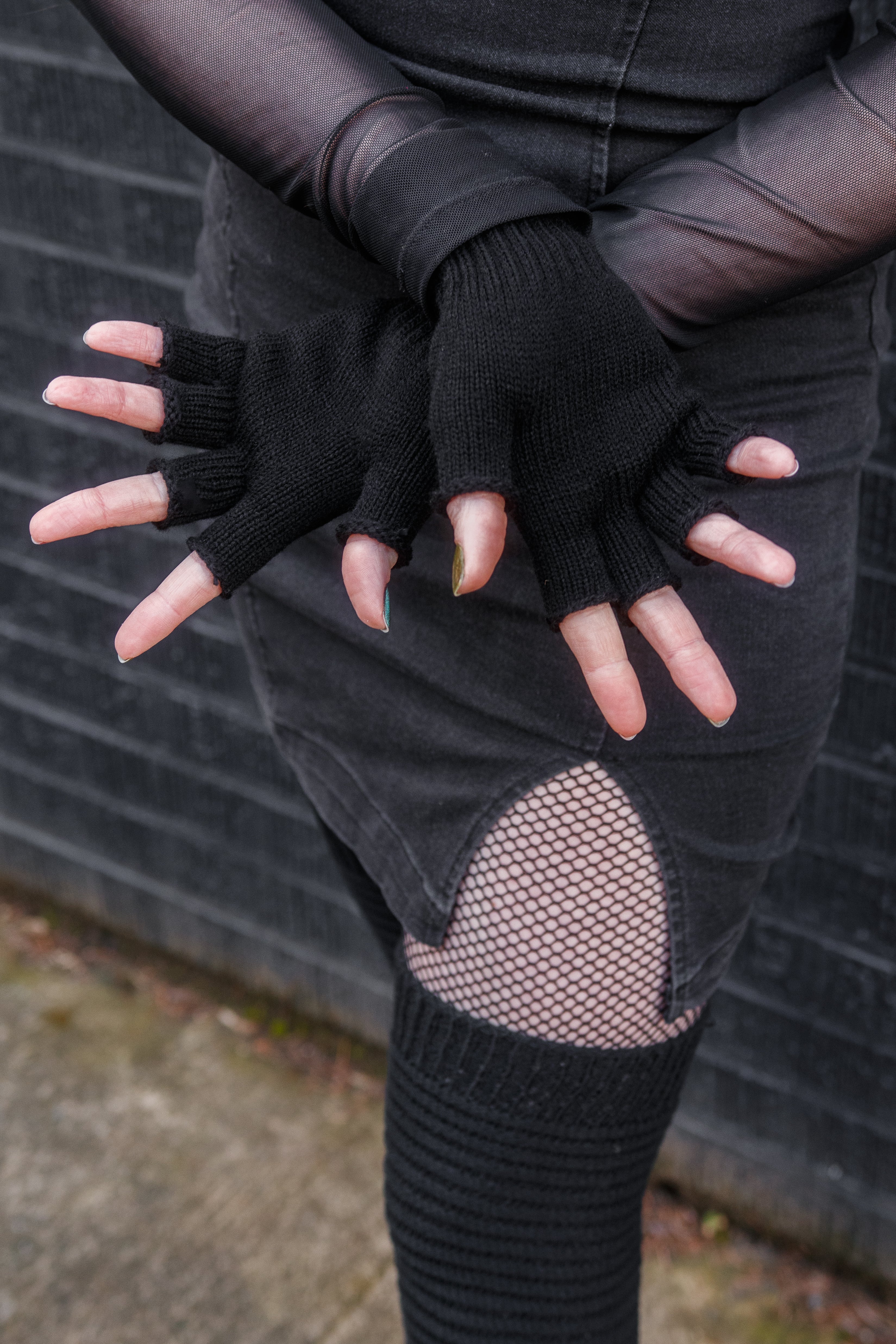 A person wearing knit fingerless gloves in black