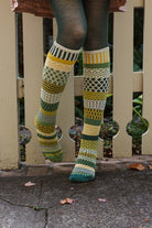 A person wearing fiddlehead knee high socks in various greens