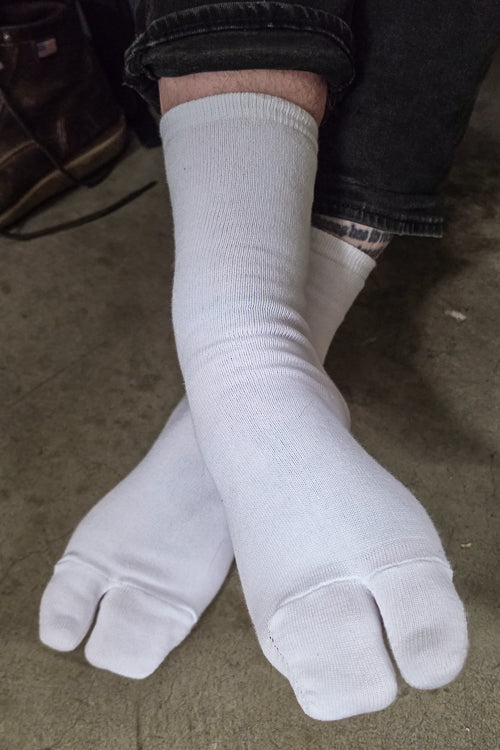 A person wearing white, large foot Tabi Socks