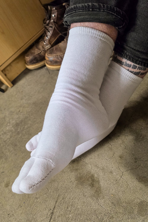 A person wearing white, large foot Tabi Socks