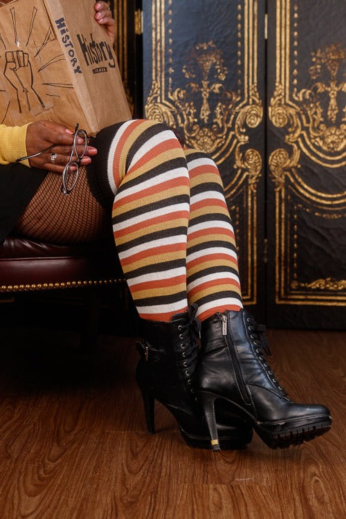 United Extraordinary Thigh High, worn by a model who is reading a book about Black history